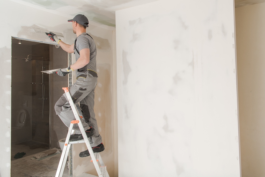 Caucasian Worker in His 30s Patching Drywall Inside Newly Developed House.